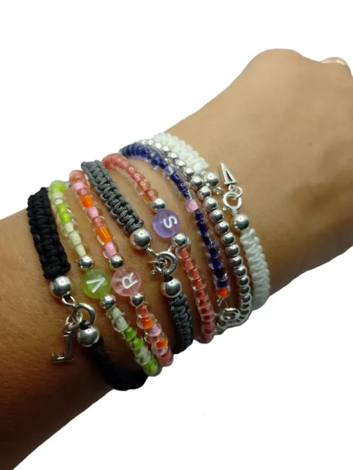 pulseras diferentes acabados de macrame y colores, todas ellas con bolas de plata y iniciales.